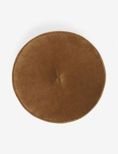 a brown round cushion sitting on top of a white surface