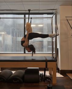 a woman doing a handstand on top of a bench in front of a window