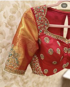 a red blouse with gold and green details on the shoulders, hanging from a hanger