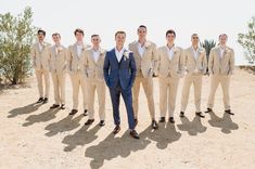 a man standing in front of a group of men wearing tan suits and white shirts