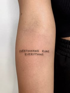 a woman with a tattoo on her arm that says, overthiking runs everything