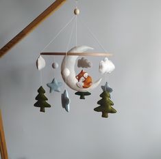 a baby crib mobile with a fox sleeping on the moon and stars hanging from it