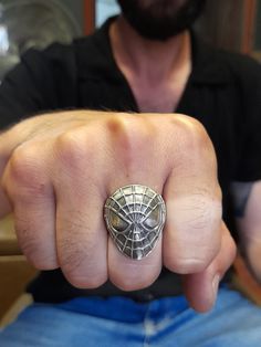 a man wearing a spiderman mask ring on his thumb and pointing at the camera