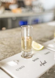 a glass filled with liquid sitting on top of a counter next to a slice of lemon