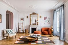 a living room with white walls and wood flooring is furnished with orange chairs, a coffee table, and a fireplace