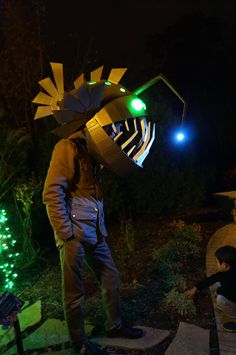 a man is standing in the dark with an umbrella on his head and lights behind him