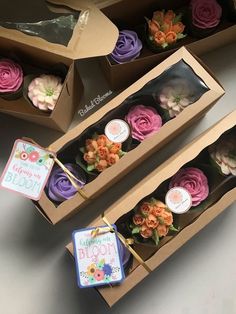 two boxes filled with different colored cupcakes on top of a white table next to each other