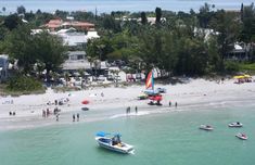 people are on the beach with boats in the water