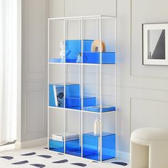 a young boy standing in front of a book shelf with blue bins on it