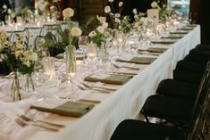 a long table is set with white flowers and candles