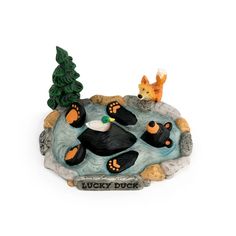 a figurine of a dog laying on top of a rock next to a tree