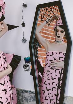 two mannequins dressed in pink and black are standing next to a mirror