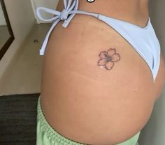 a woman's stomach with a small flower tattoo on the side of her belly