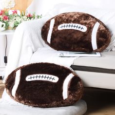 two football pillows sitting on top of a bed