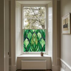 a stained glass window in the corner of a room with wood flooring and white walls