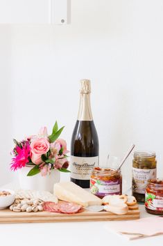 a table topped with lots of different types of food and bottles of wine on top of it