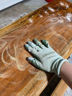 a person with gloves on their hands is sanding down a piece of wood that has been stained green