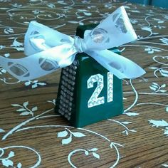 a small green box with a white bow on it sitting on top of a table