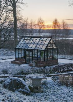 a small glass house sitting in the middle of a snow covered field