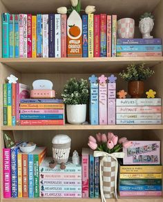 a book shelf filled with lots of books next to a potted plant and flowers