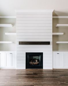 an empty living room with a fireplace and shelves