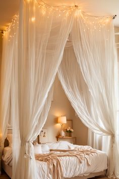 a canopy bed with white drapes and string lights