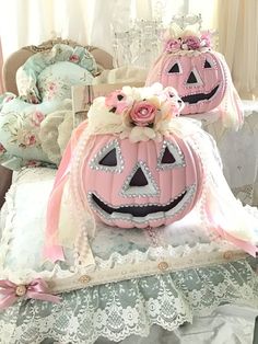 two carved pumpkins sitting on top of a table next to pillows and lace doily