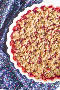 a pie sitting on top of a table covered in crumbled toppings next to a blue and white cloth