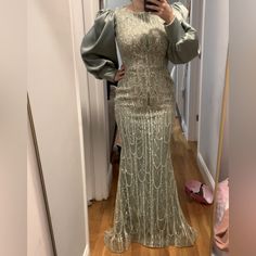 a woman taking a selfie in a mirror wearing a long dress with puff sleeves