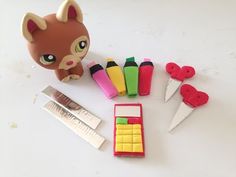 an assortment of toy items including scissors, markers and erasers on a white surface