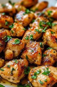 a plate full of chicken with parsley on the top and sauce in the middle