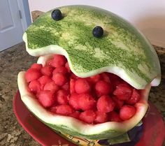 a watermelon sculpture made to look like a frog's mouth with berries in it