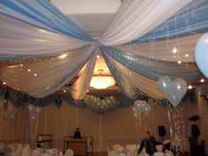 the ceiling is decorated with white and blue balloons, streamers, and draping