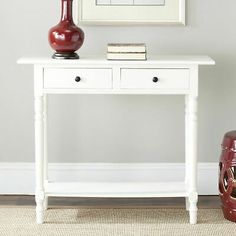 a white table with two drawers and a vase on top