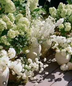 white vases filled with flowers sitting on a wooden table next to eachother