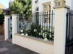 a white house with black iron fence and flowers