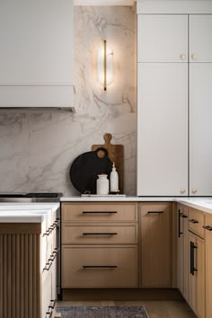 a kitchen with marble counter tops and wooden cabinets, along with white cupboards on both sides