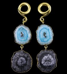 two pieces of gold and blue agate stone hanging from earwires on black background