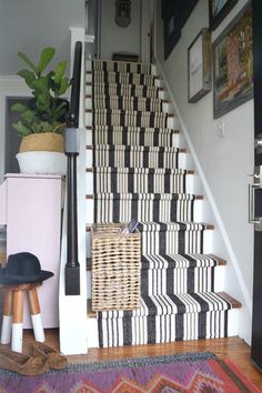 the stairs are decorated with black and white striped rugs, which also have woven baskets on them