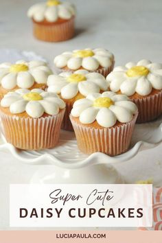 cupcakes with white frosting and yellow flowers on top are sitting on a cake plate