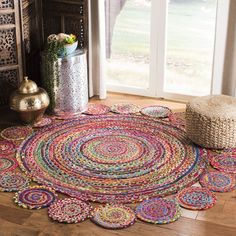 a multicolored round rug is on the floor next to a vase with flowers