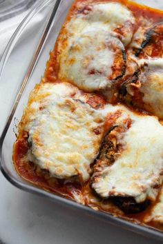 a casserole dish with cheese and sauce in it on a white tablecloth