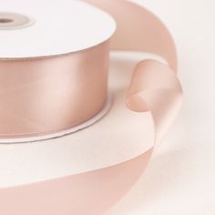 a roll of pink satin ribbon sitting on top of a white table