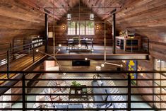 an open living room and dining area in a wooden house with exposed ceilings, wood paneling, and metal railings