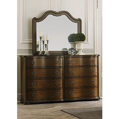 a dresser with a mirror on top of it next to a vase filled with flowers