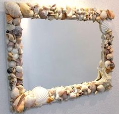 there is a mirror made out of seashells on the wall and it's frame