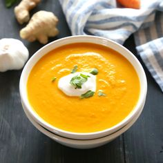 a white bowl filled with carrot soup and topped with sour cream, garnished with parsley