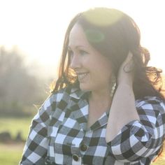 a woman with long hair wearing a black and white checkered shirt is talking on her cell phone