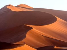 a person standing on top of a large sand dune in the middle of the desert