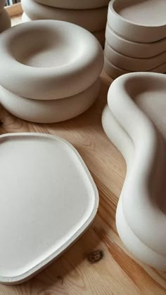 there are many white bowls and plates on the table